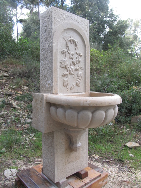 Fontaine en pierre avec ornementation de fruits en fresque.